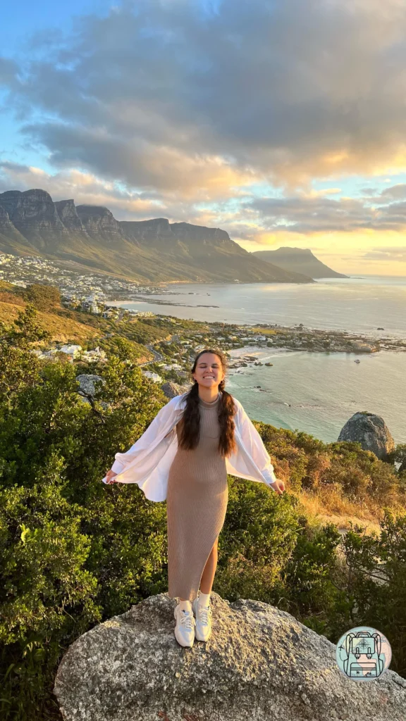 Teresa en una gran roca con una vista panorámica de la costa de Clifton y los picos de los Doce Apóstoles al atardecer