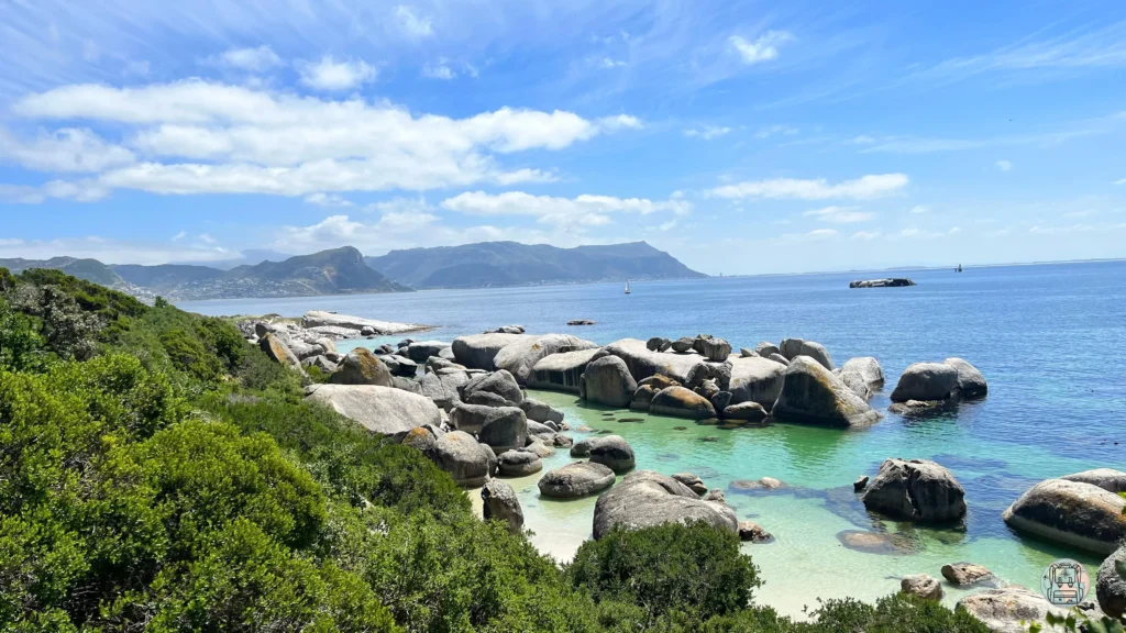 Playa de aguas turquesas rodeada de grandes rocas de granito y vegetación verde bajo un cielo despejado