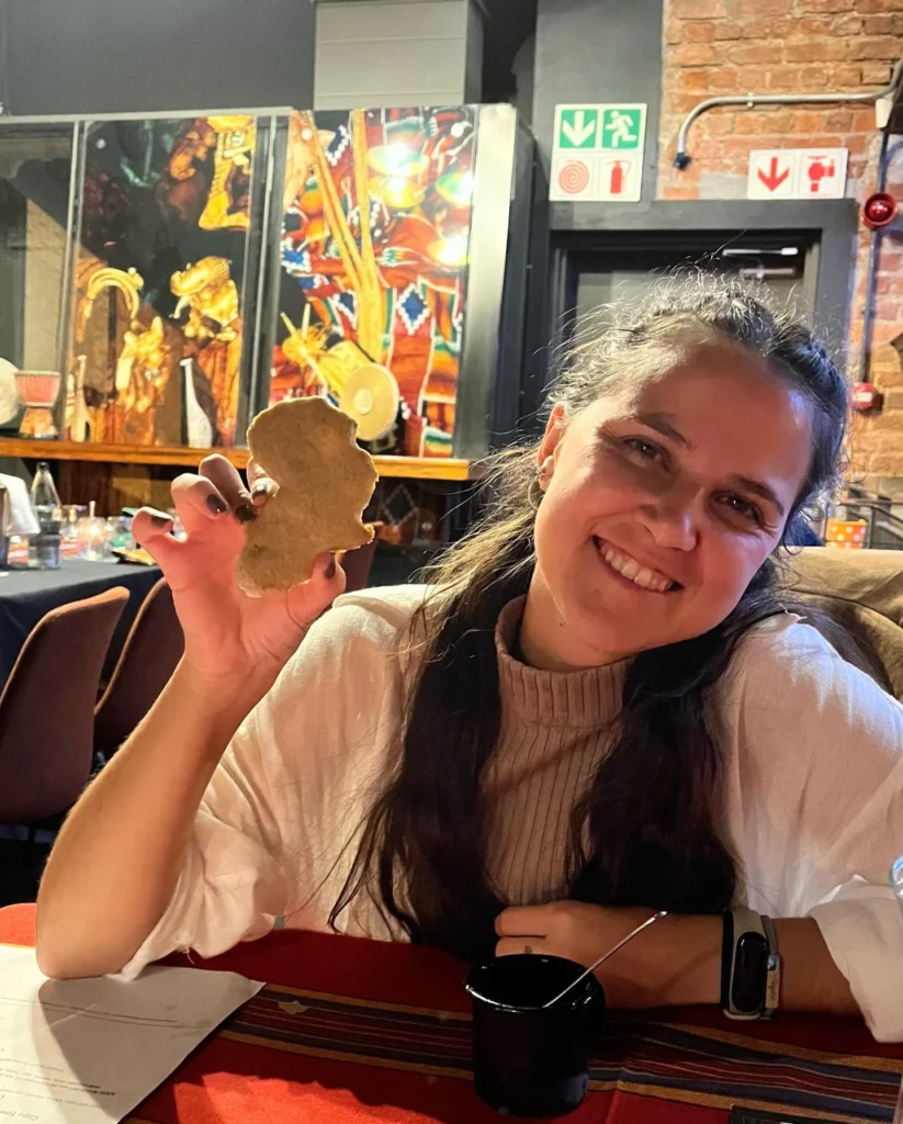 Mujer sonriendo mientras muestra una galleta con la forma del continente africano