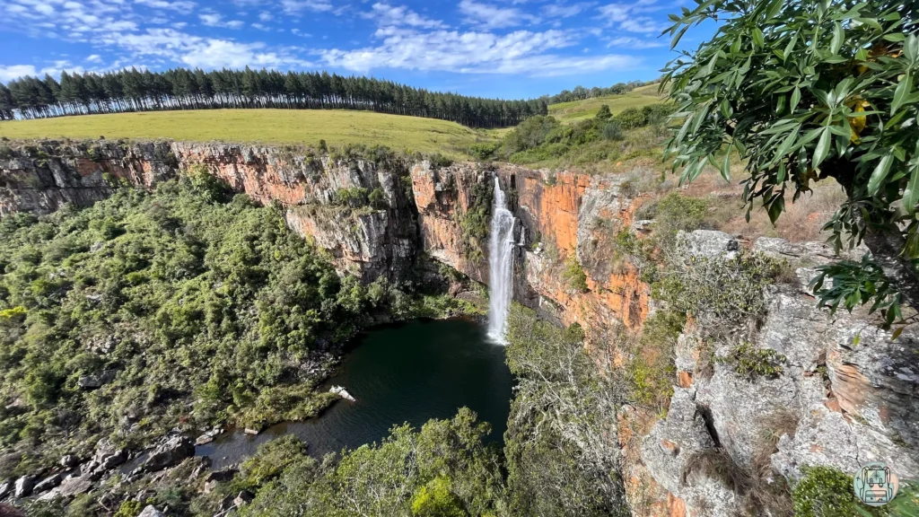 Cascada Berlin Falls cayendo sobre un acantilado de roca roja hacia una poza verde en Sudáfrica