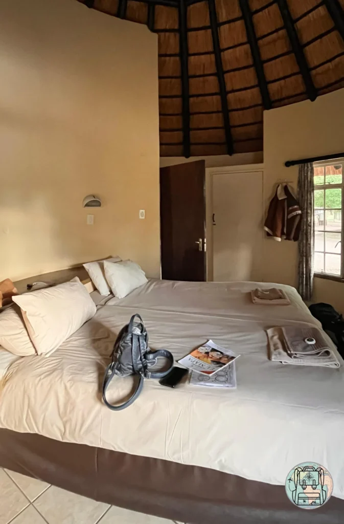 Interior de bungalow en Satara donde alojarse en el Parque Kruger con camas individuales unidas y techo cónico de paja